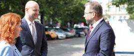 Minister funduszy i polityki regionalnej Grzegorz Puda stoi na chodniku, przed nim stoją wicepremier Republiki Słowacji ds. planu odbudowy i funduszy europejskich Lívia Vašákova oraz minister inwestycji, rozwoju regionalnego i informatyzacji Republiki Słowackiej Peter Balík 