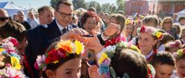 Premier z dziewczynkami w strojach ludowych.