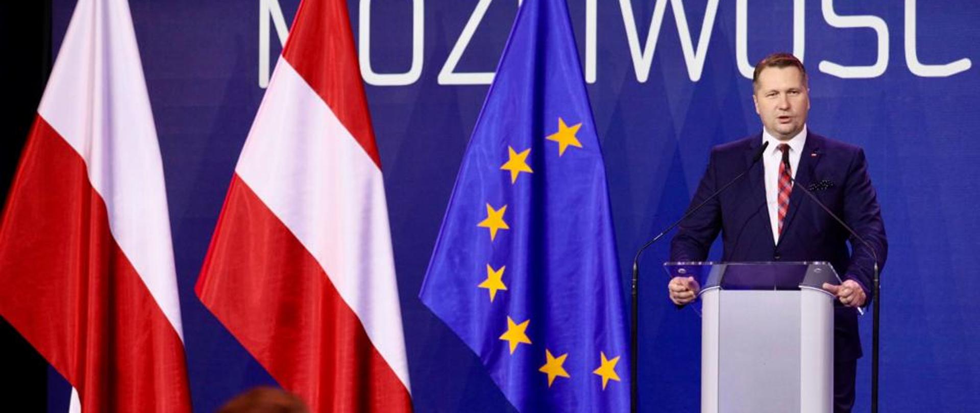 minister Przemysław Czarnek podczas konkresu 590 przemawia do mikrofonu przy mównicy. 