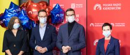 Grupa osób stoi na tle ścianki Polskiego Radia wśród nich Premier Morawiecki, minister Buda, poseł Lichocka i prezes Kamiński 
