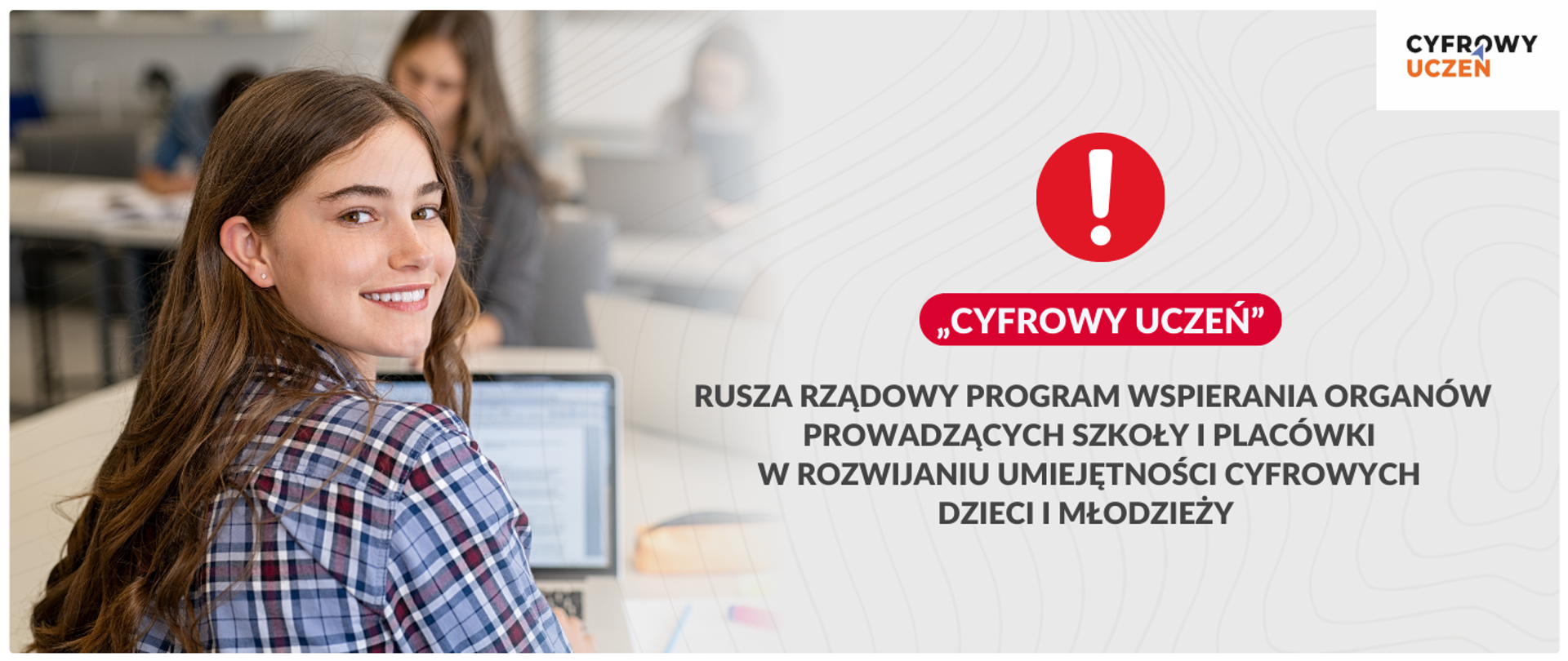 Po lewej stronie grafiki znajduje się zdjęcie uśmiechniętej młodej kobiety siedzącej przy biurku i patrzącej wprost w obiektyw. Ma na sobie koszulę w czerwoną i granatową kratę. Przed nią widoczny jest otwarty laptop. W tle widać inne osoby pracujące przy biurkach. Prawa część grafiki ma jasne, jednolite tło. Na samej górze widoczne jest logo „Cyfrowy uczeń”. Poniżej, w centralnej części, znajduje się duża, czerwona ikona z wykrzyknikiem. Obok niej umieszczono czerwony napis w cudzysłowie: „Cyfrowy uczeń”. Pod spodem, większą czcionką, znajduje się biały napis „Rusza rządowy program wspierania organów prowadzących szkoły i placówki w rozwijaniu umiejętności cyfrowych dzieci i młodzieży”. Całość grafiki ma charakter informacyjny.