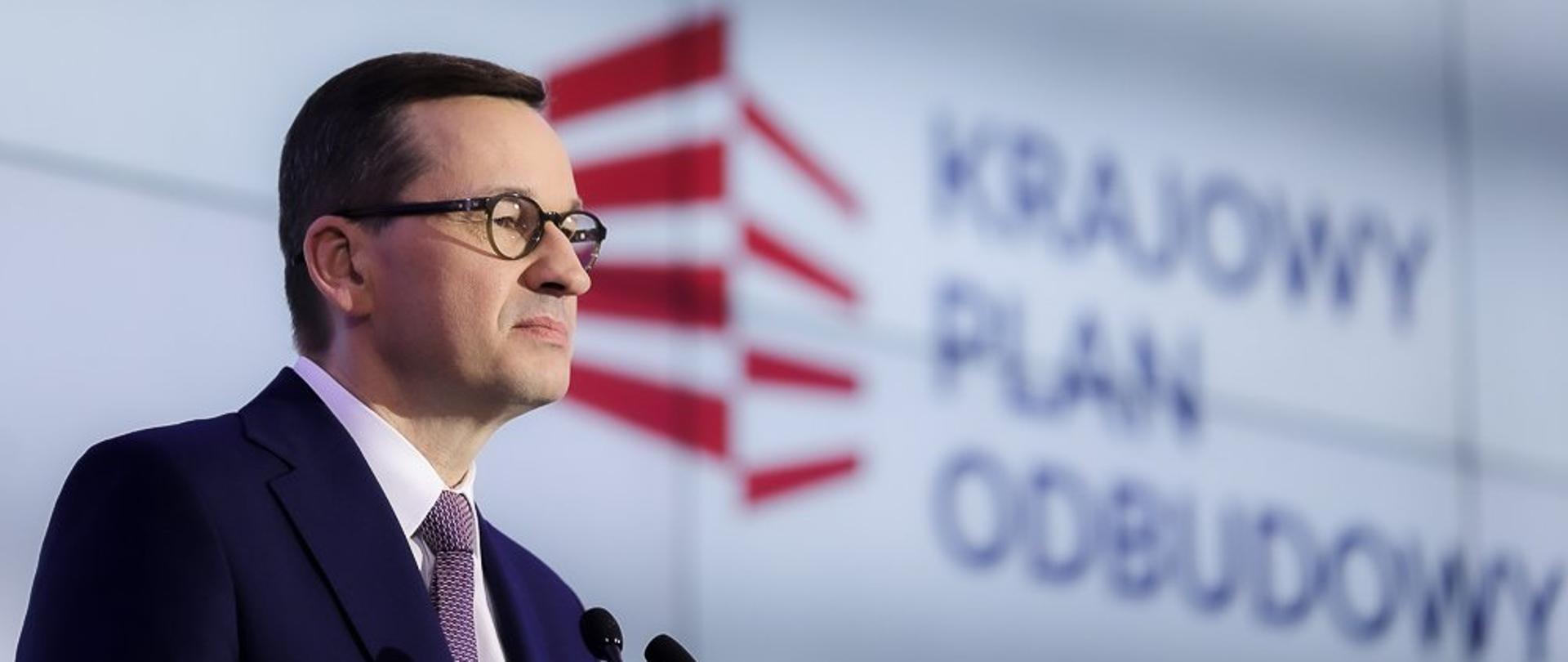 Zdjęcie portretowe premiera Mateusza Morawieckiego w tle logo Krajowego Planu Odbudowy