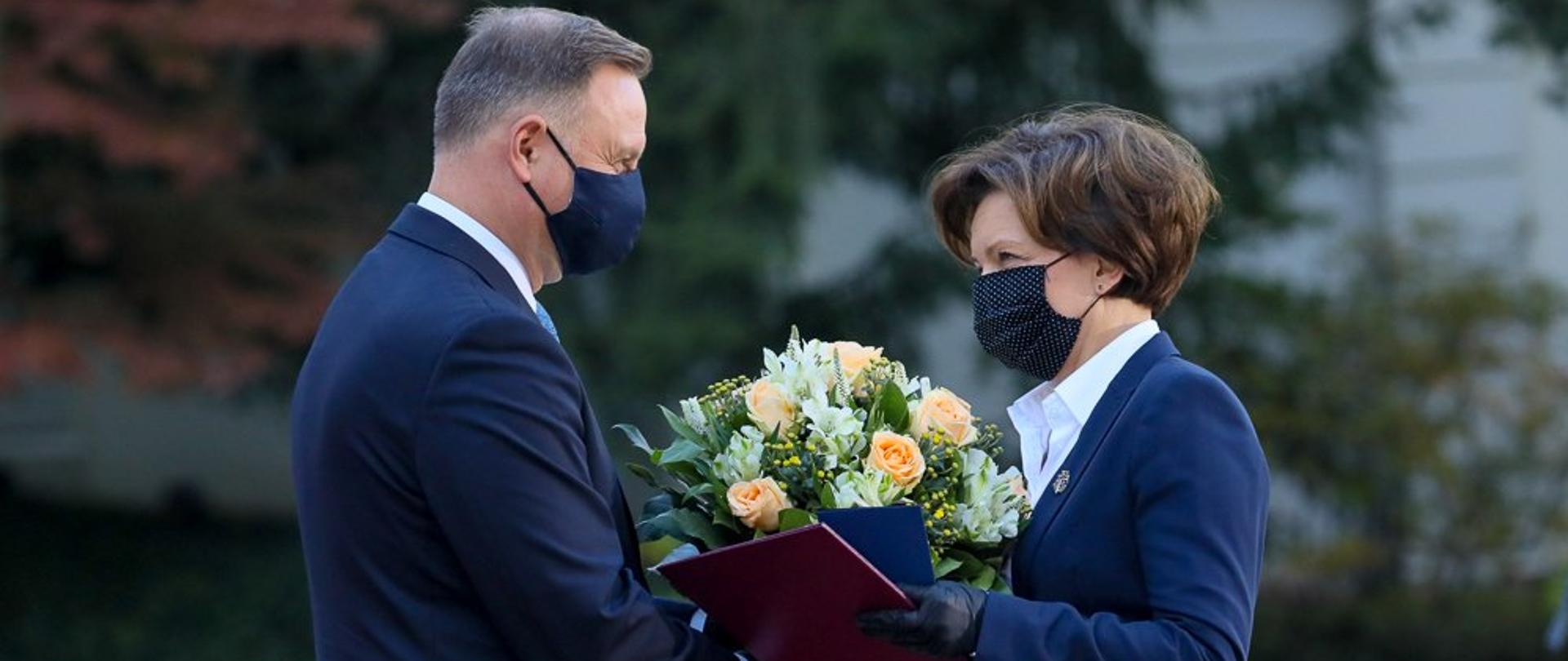Ogrody pałacu Prezydenckiego. Prezydent Duda wręcza nominację na stanowisko ministra rodziny i polityki społecznej Marlenie Maląg. Wręcza bukiet kwiatów.