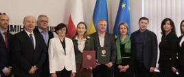 Minister funduszy i polityki regionalnej Katarzyna Pełczyńska-Nałęcz stoi z podpisaną umową, po obu jej stronach stoją członkowie polskiej i ukraińskiej delegacji