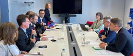 Minister funduszy i polityki regionalnej Grzegorz Puda i komisarz do spraw miejsc pracy i praw socjalnych Nicolas Schmit siedzą przy na przeciw siebie przy owalnym stole, obok nich siedzą pozostali uczestnicy spotkania
