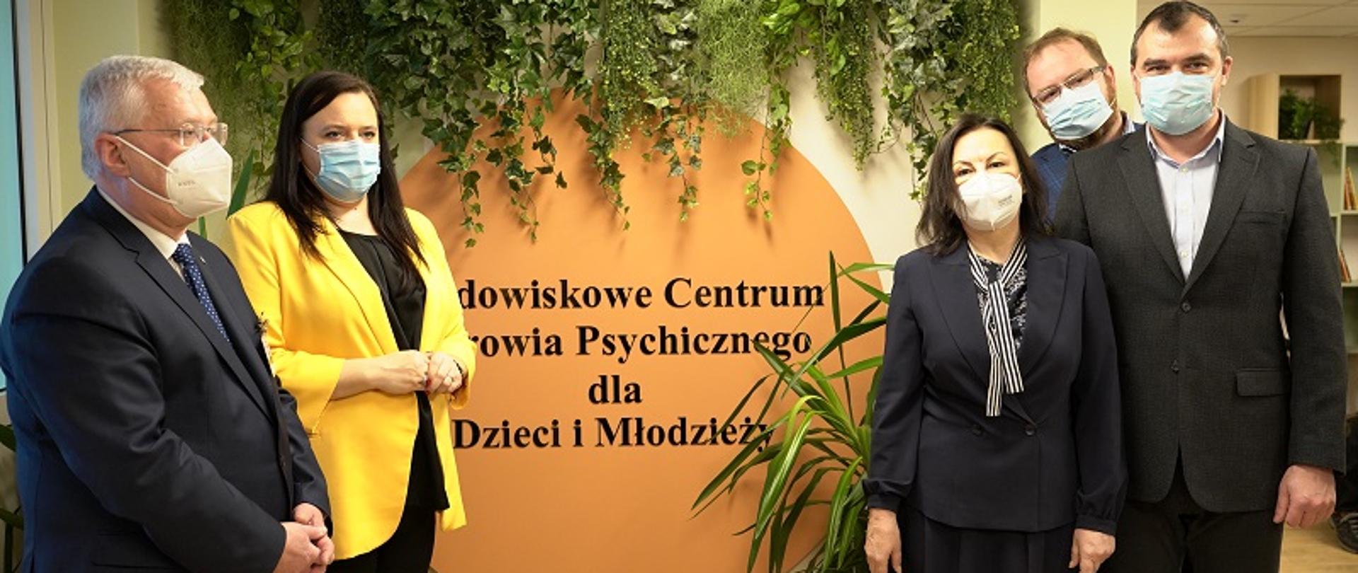 5 osób stoi na tle napisu Środowiskowe Centrum Wsparcia Psychicznego dla Dzieci i Młodzieży