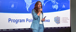 dyrektor Wanda Buk przemawia do publiczności. W tle prezentacja multimedialna