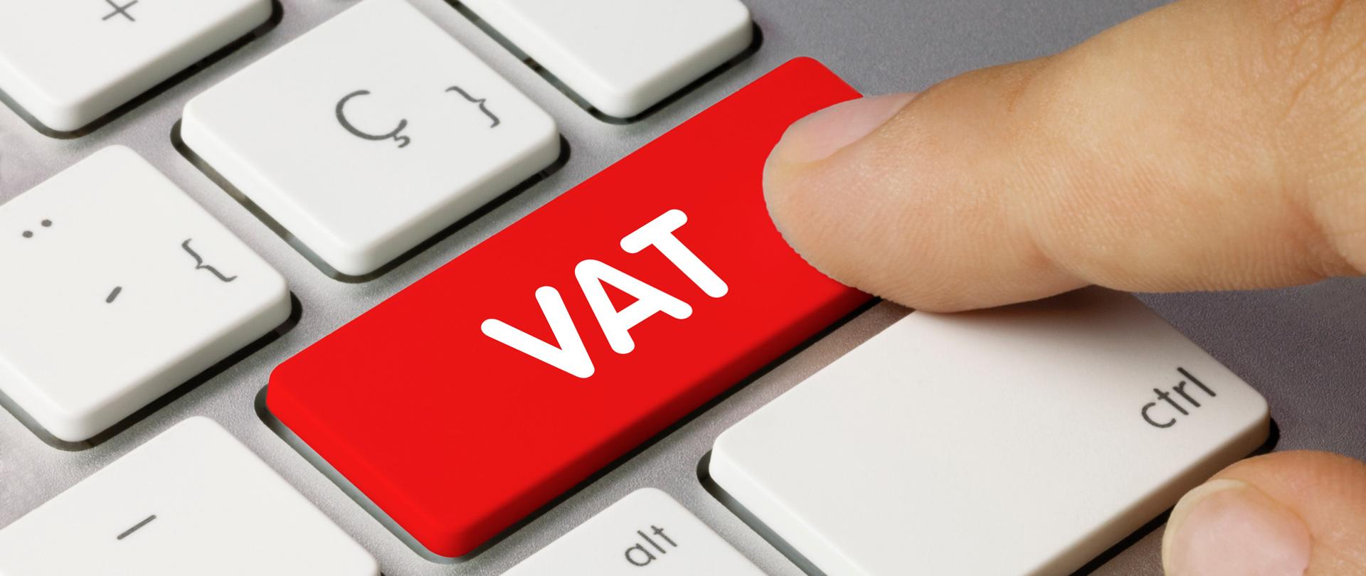 Palec wskazuje na klawiaturę, na czerwony guzik z napisem VAT.