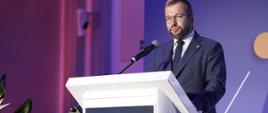 Minister funduszy i polityki regionalnej Grzegorz Puda. na konferencji pn. "Efektywność w PPP", minister stoi przy mównicy i przemawia do mikrofonu
