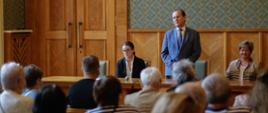 Spotkanie wiceministra edukacji i nauki Włodzimierza Bernackiego z grupą repatriantów z Rosji, Kazachstanu, Gruzji i Uzbekistanu.
Minister stoi pośród siedzących gości.