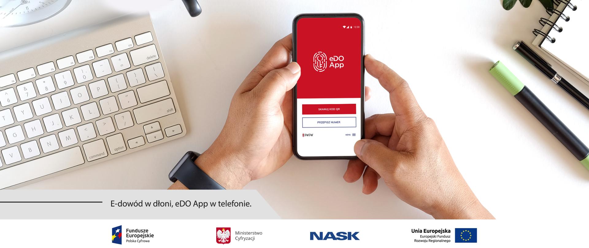 Grafika. Smartfon z włączoną aplikacją eDOApp. Obok napis: E-dowód w dłonie, eDO App w telefonie.