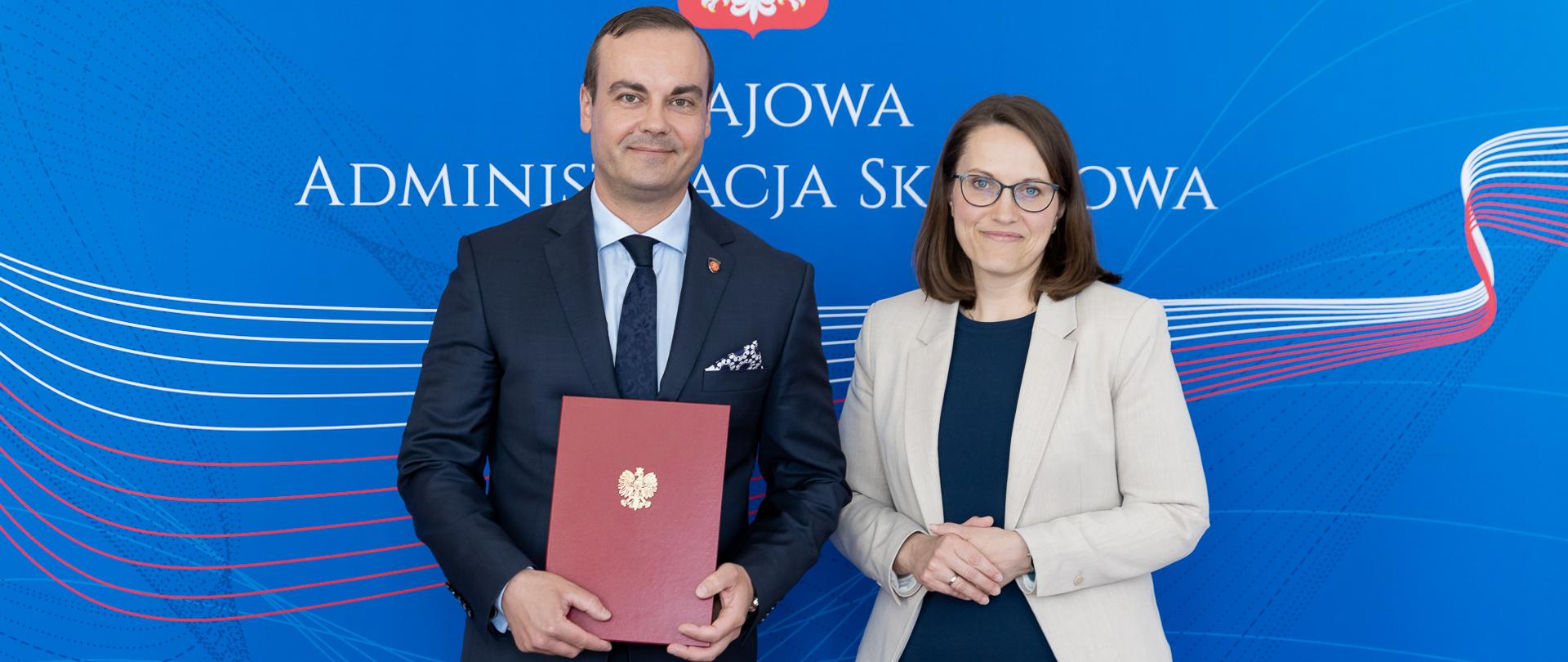 Minister Finansów Małgorzata Rzeczkowska i Szef KAS Bartosz Zbarszczuk na tle banera Krajowe Administracji Skarbowej