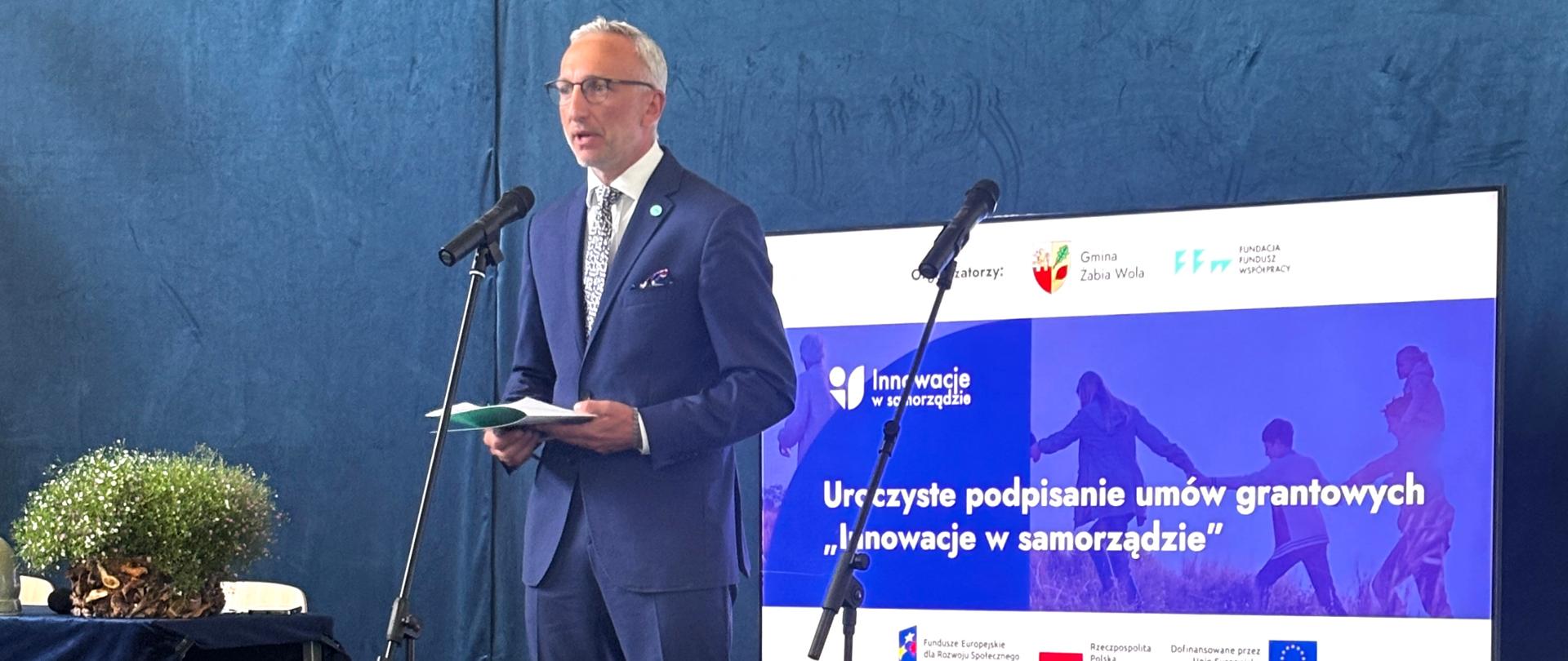 Na zdjęciu mężczyzna stoi przed mikrofonem