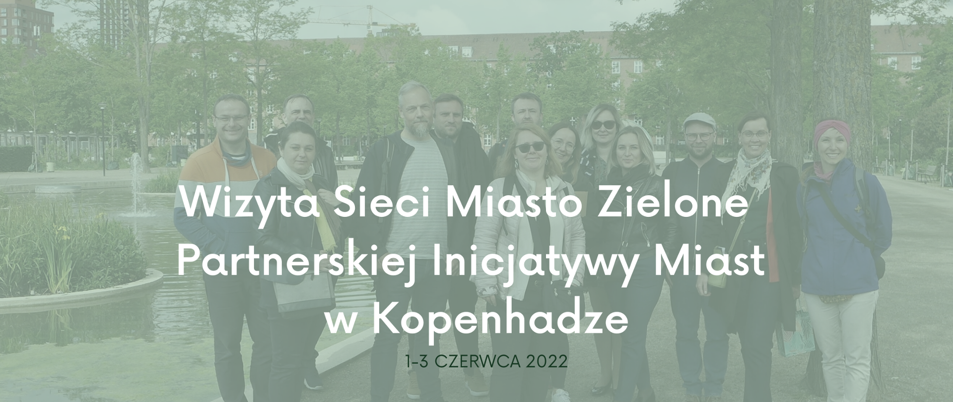 Grupa osób stojących na tle zieleni. Na zdjęciu napis: "Wizyta Sieci Miasto Zielone Partnerskiej Inicjatywy Miast w Kopenhadze". 