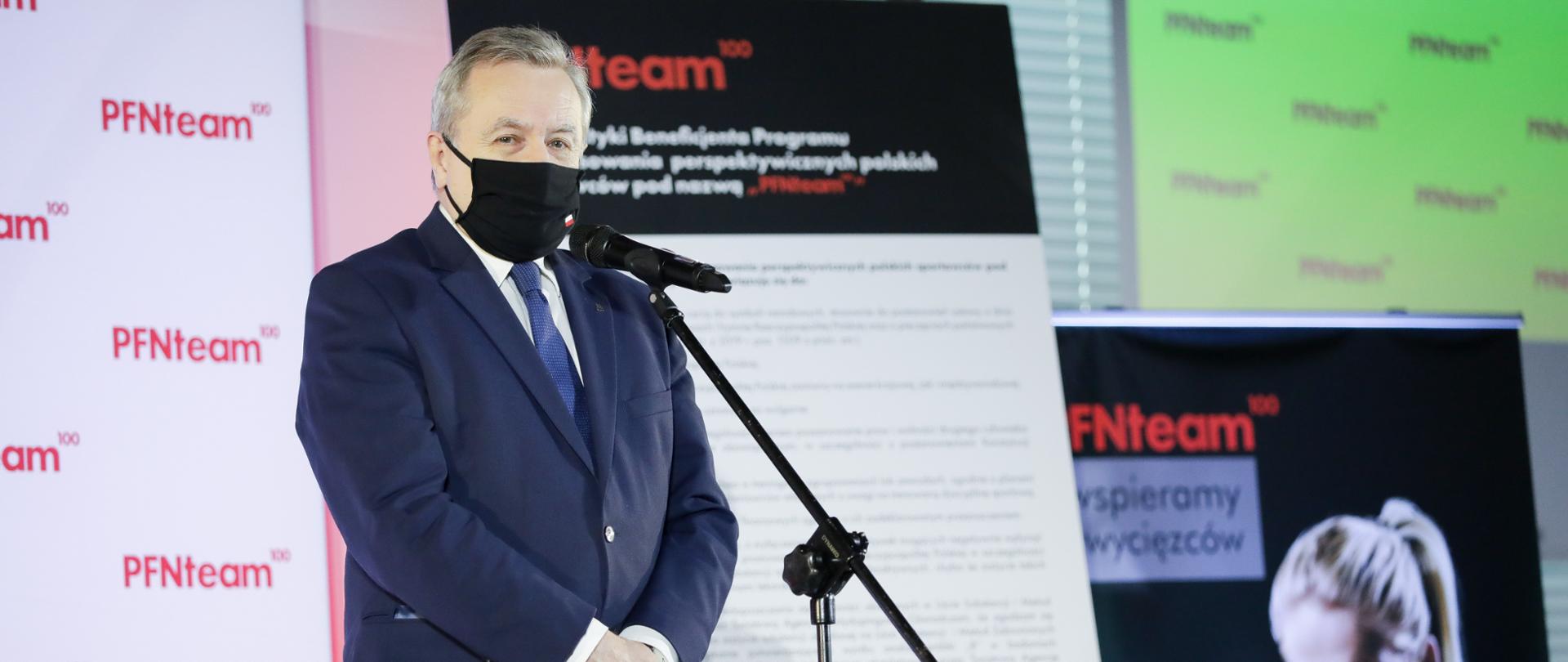 Wicepremier Piotr Gliński stoi przed mikrofonem.