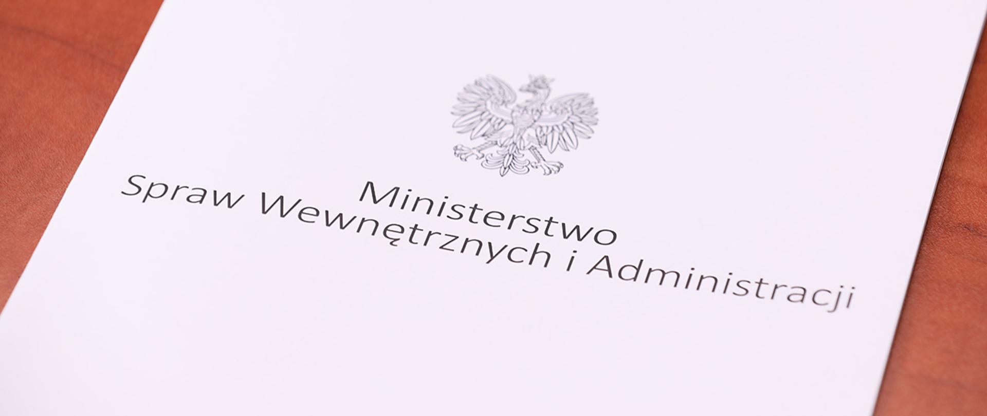Teczka MSWiA leżąca na drewnianej powierzchni