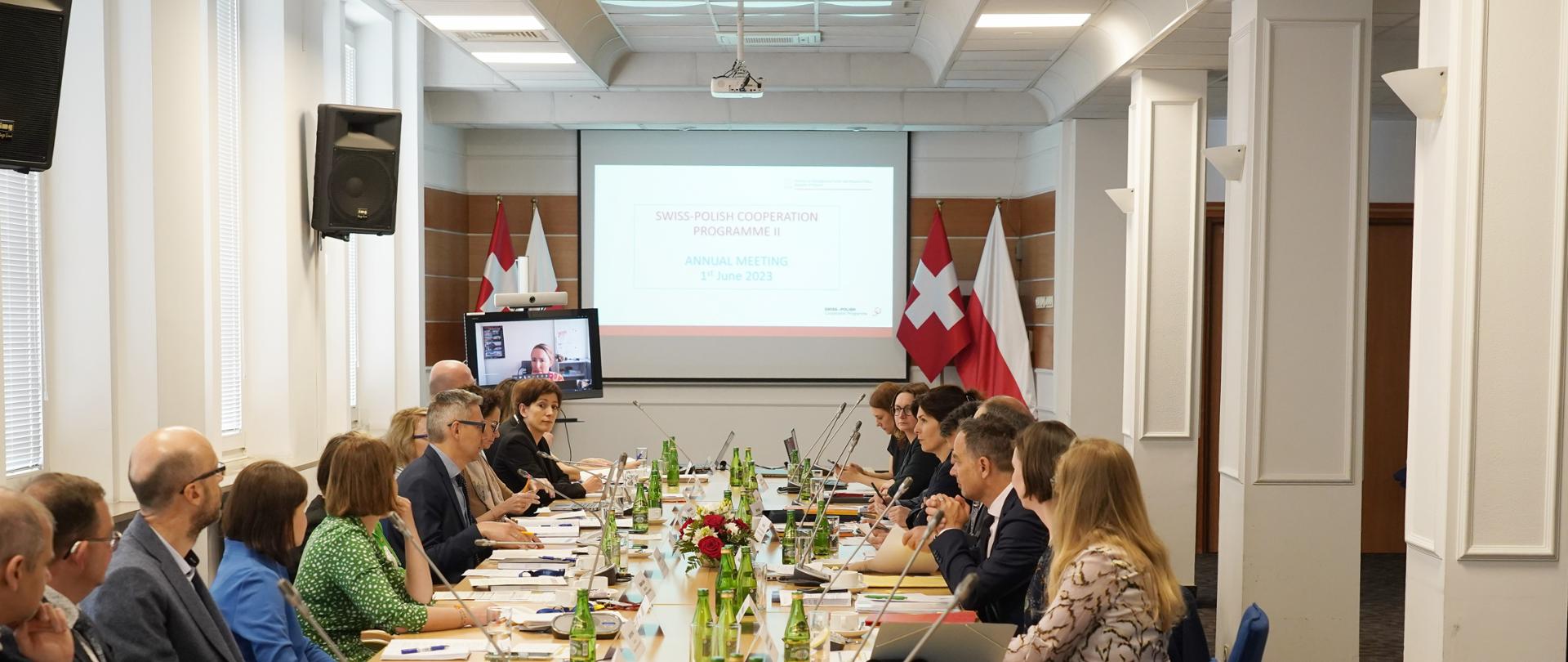 Grupa osób siedzi przy stołach podczas konferencji.