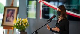 Minister Sportu Danuta Dmowska-Andrzejuk stojąca w maseczce przed mikrofonem, przemawia.