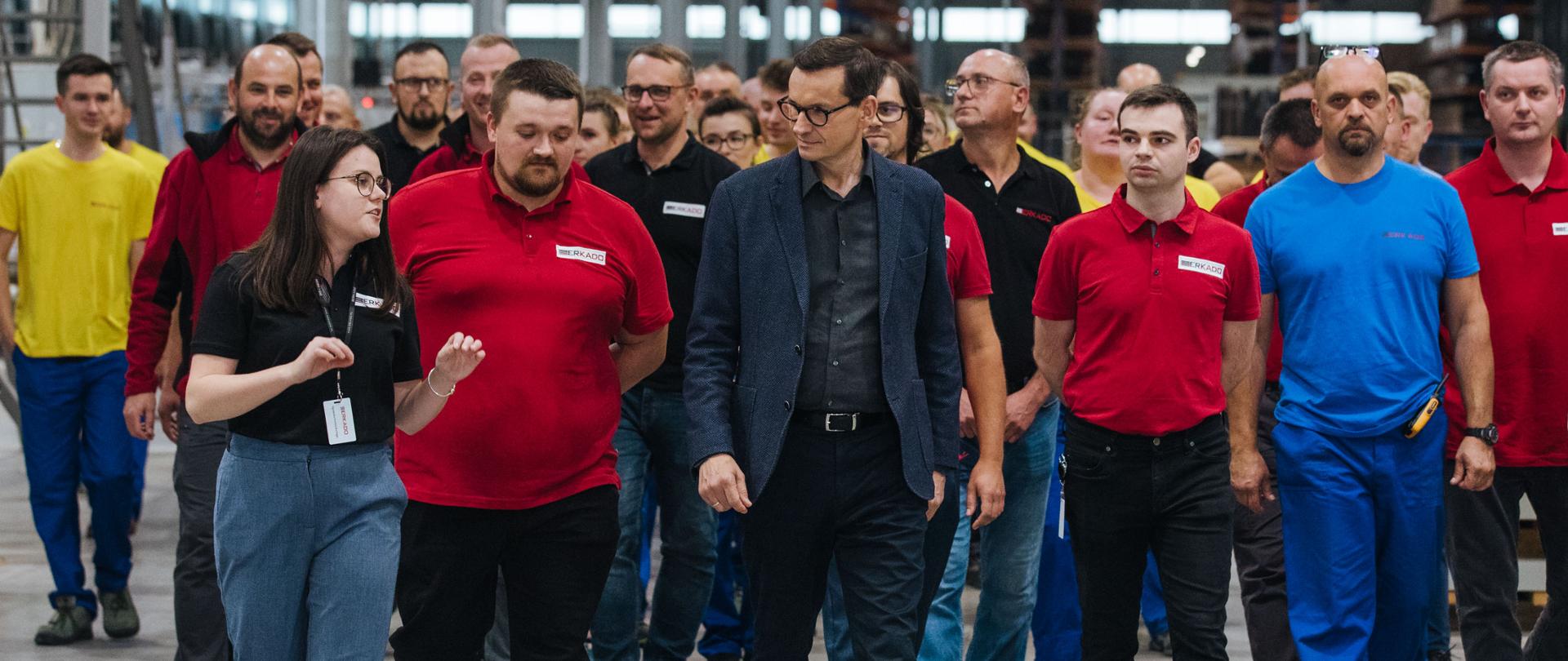 Premier na tle pracowników firmy.