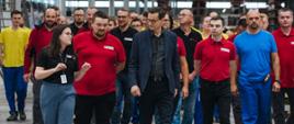 Premier na tle pracowników firmy.