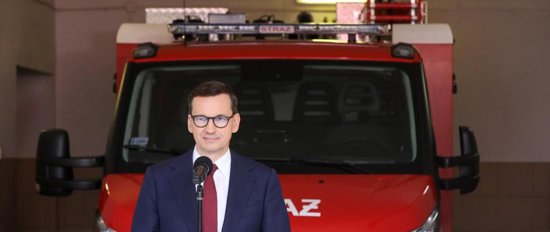Premier na tle wozu strażackiego.