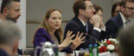 Minister Katarzyna Pełczyńska-Nałęcz siedzi z lewej strony przy stole i mówi do mikrofonu. 