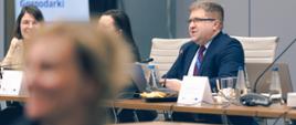 Na zadjęciu widać uczestników spotkania siedzących przy stole konferencyjnym