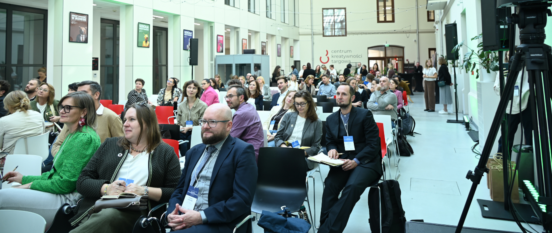 Publiczność zgromadzona w jasnym, wielopoziomowym atrium budynku Centrum Kreatywności Targowa podczas wydarzenia GOZDezInfoLAB.
