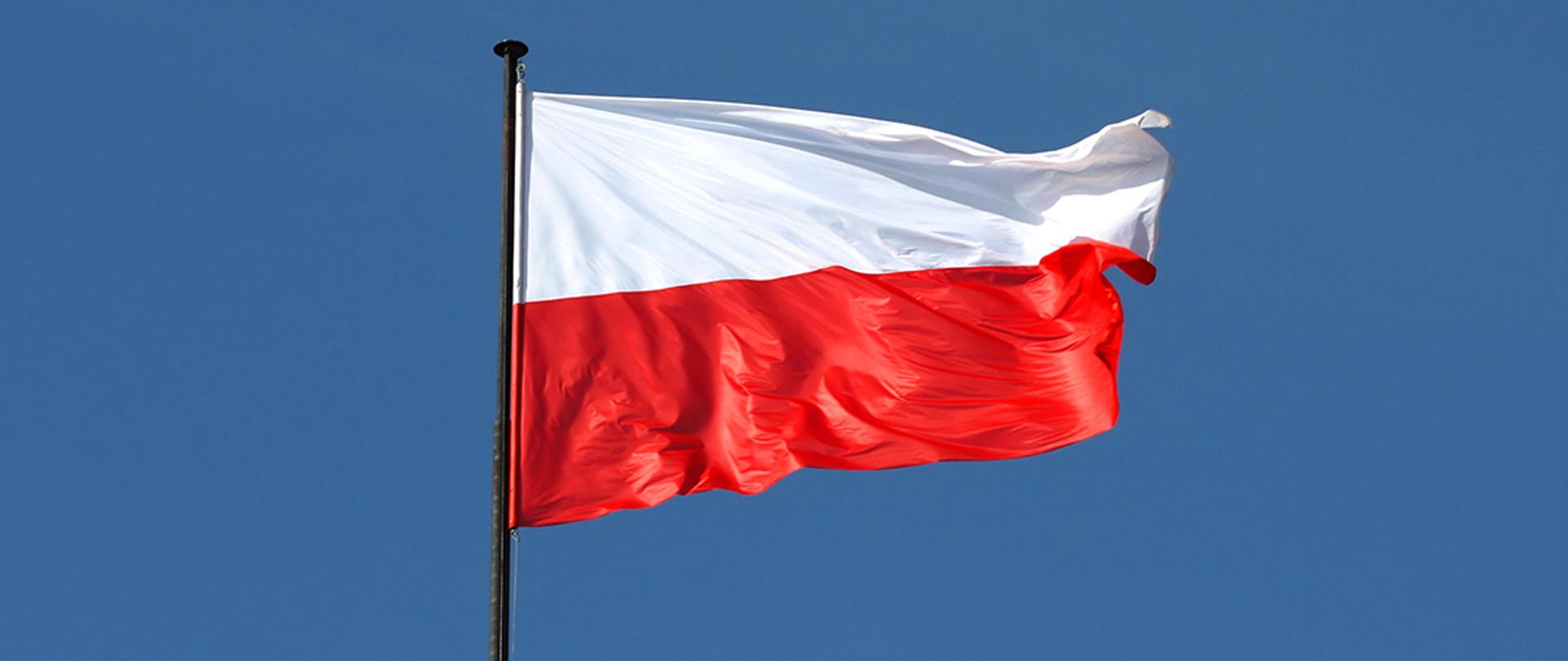 Biało-czerwona flaga Polski powiewająca na maszcie.