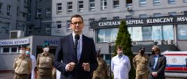 Premier Mateusz Morawiecki stoi podczas konferencji prasowej.