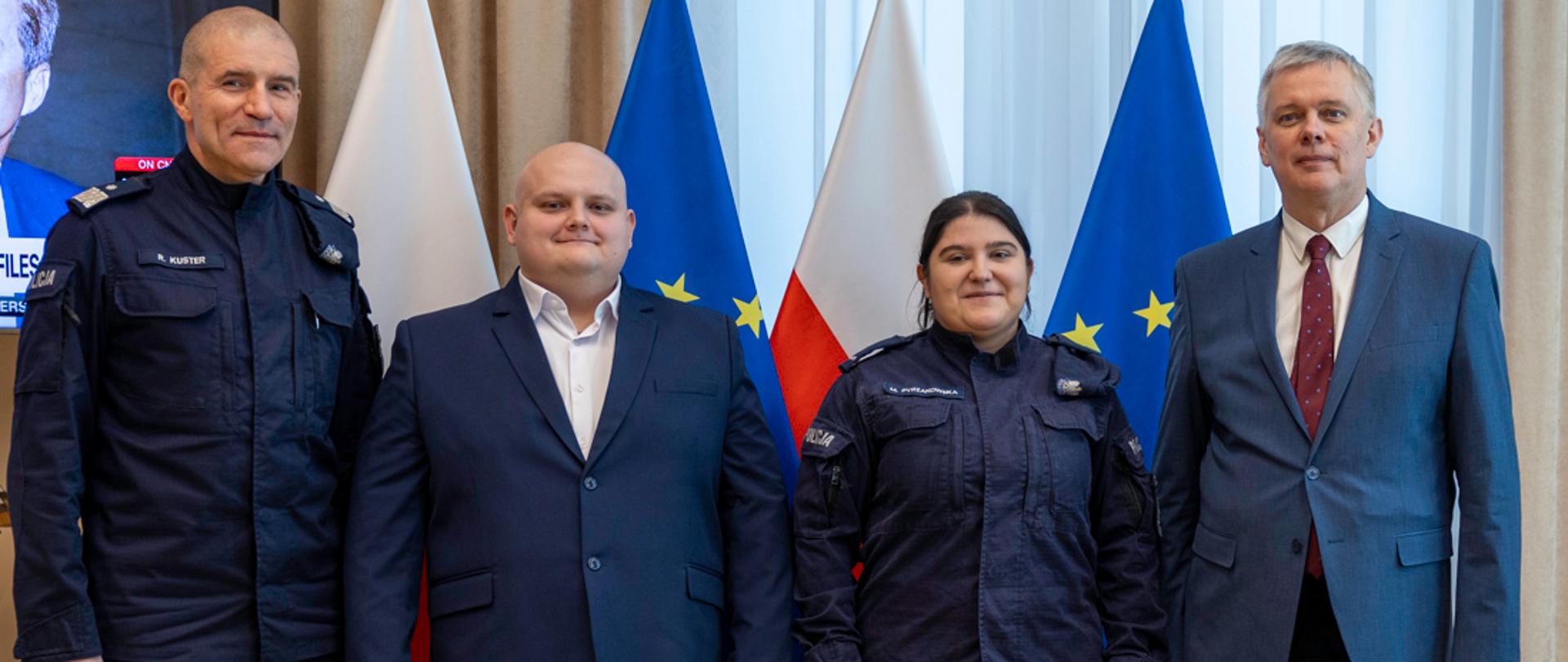 Na zdjęciu cztery osoby stojące na tle flag Polski i UE