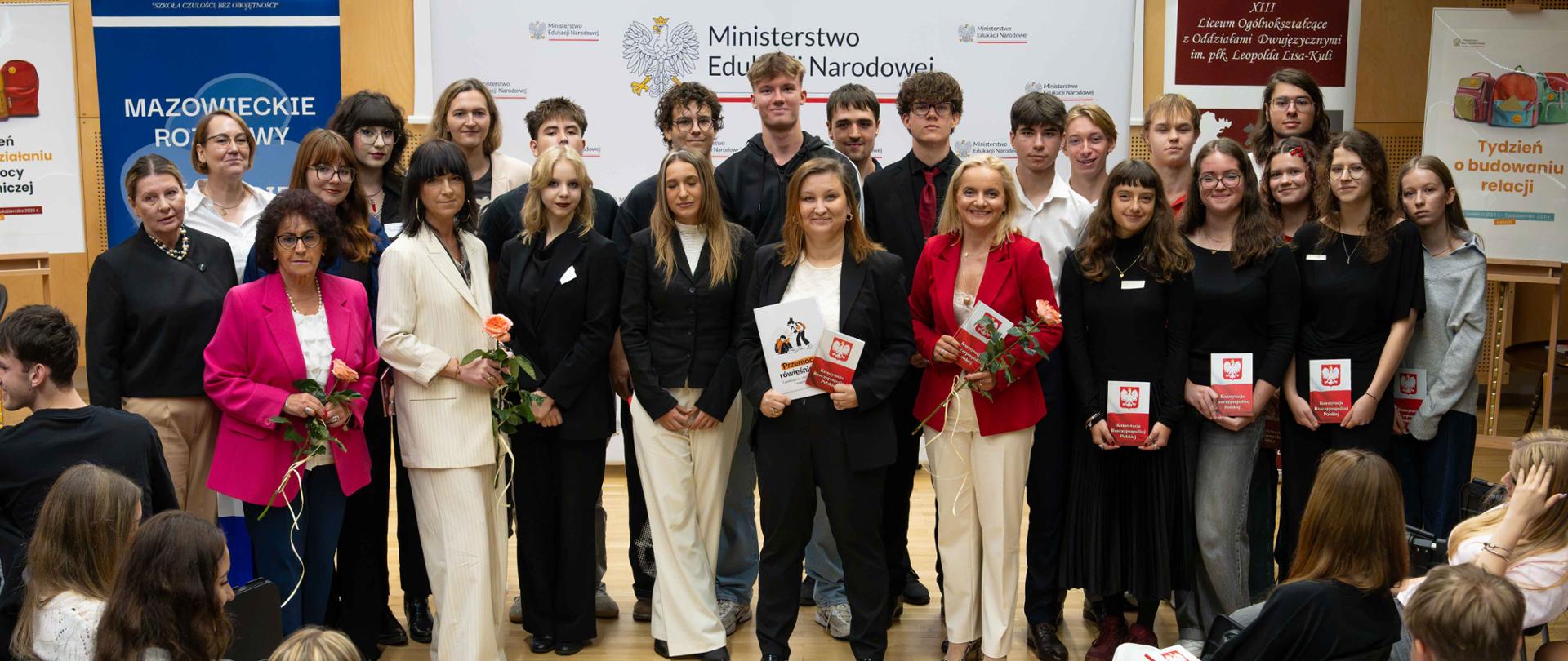 Pamiątkowe zdjęcie grupowe uczestników wydarzenia — w tym Podsekretarz Stanu Pauliny Piechny-Więckiewicz, zaproszonych gości oraz uczniów — stojących w sali na tle ścianki Ministerstwa Edukacji Narodowej.