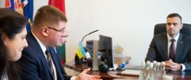 Minister i kilka innych osób siedzą przy stole i rozmawiają.