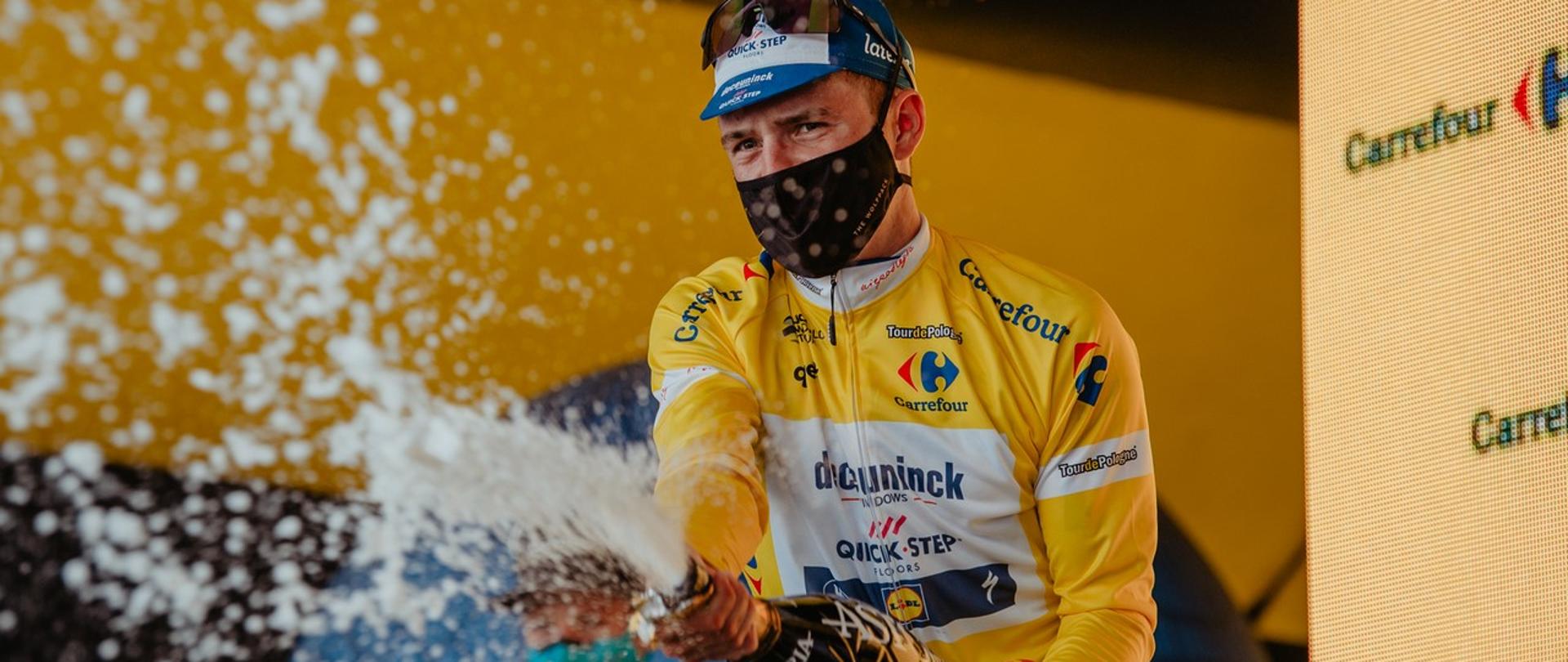 Remco Evenepoel celebruje triumf polewając szampanem publiczność.