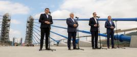 Konferencja prasowa premiera na tle mostu.