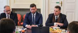 Przy stole siedzą obok siebie ministrowie edukacji i nauki, sportu i zdrowia, przed nimi otwarty laptop.
