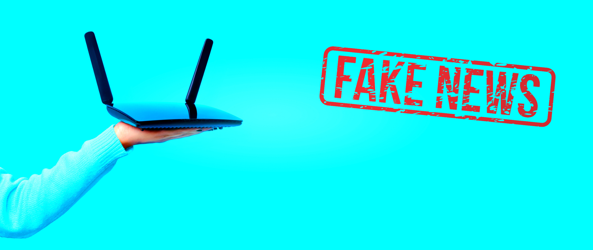 Błękitne tło. Z lewej strony - wyciągnięta ręka z trzymanym na dłoni routerem. Z prawej czerwona pieczątka "Fake news".