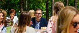 Premier siedzi i rozmawia z dzieckiem.