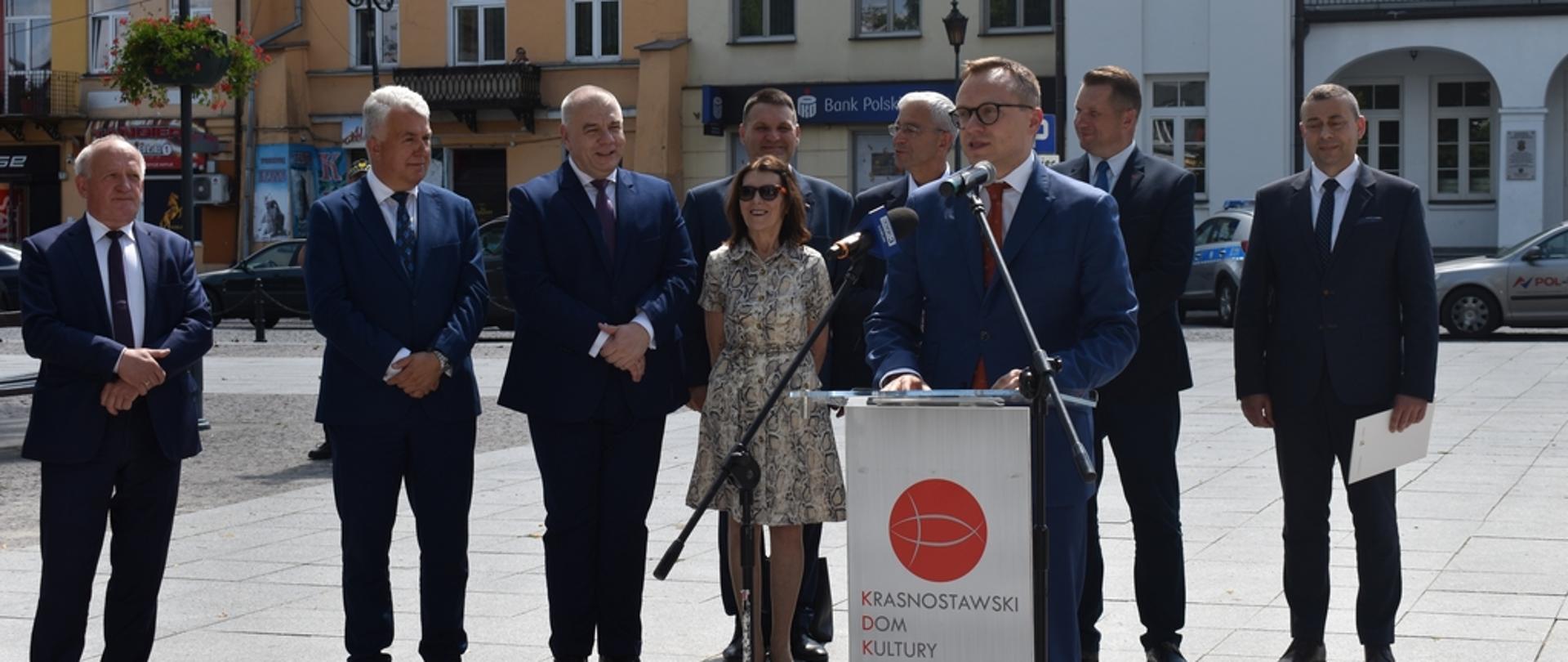 wicepremier Jack Sasin stoi w otoczeniu lokalnych samorządowców, do mikrofonu mówi wiceminister Artur Soboń