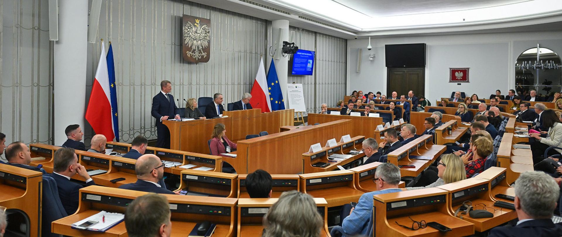 Zdjęcie przedstawiające pełną salę w Senacie. Na mównicy sekretarz stanu w Ministerstwie Sportu i Turystyki Ireneusz Raś.