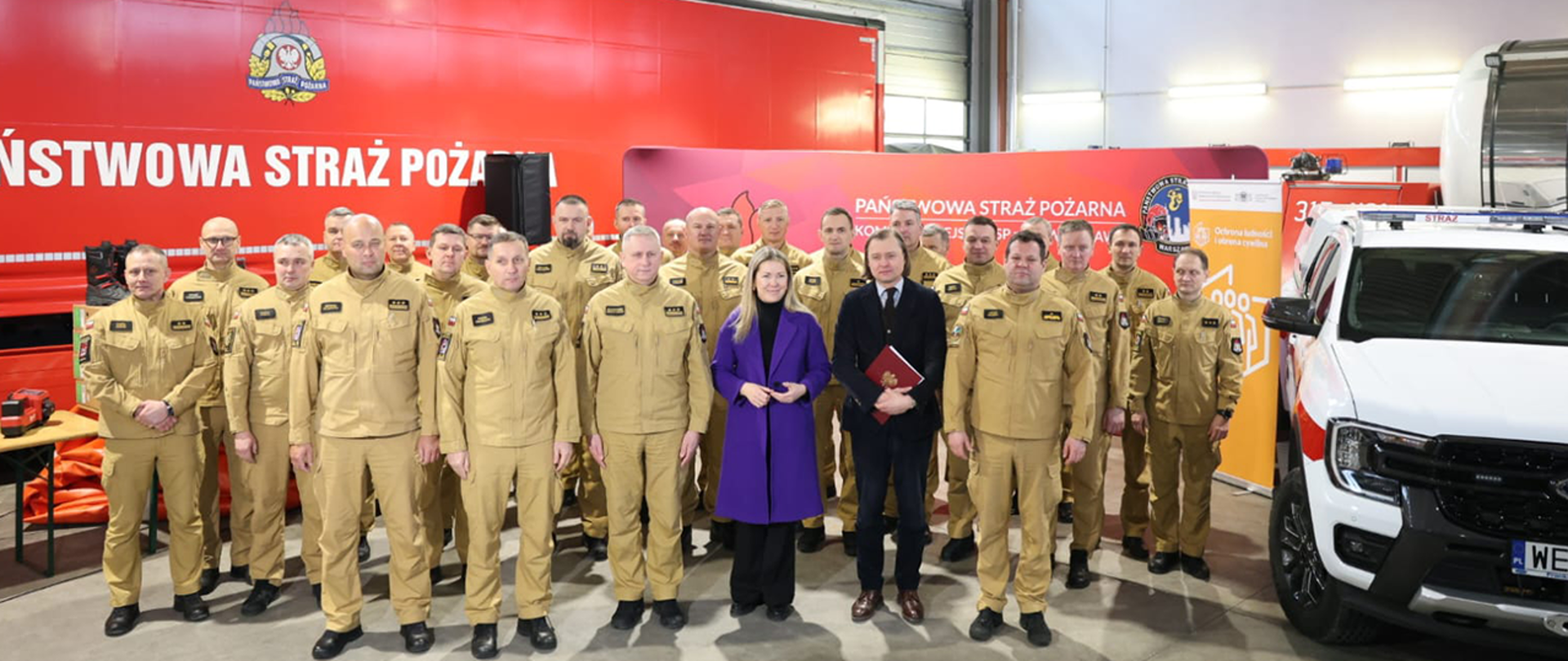 Wiceminister Magdalena Roguska, wojewoda mazowiecki Mariusz Frankowski, przedstawiciele dowództwa mazowieckiej PSP i strażacy. Z boku nowo zakupiony pojazd PSP.