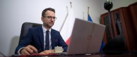 uczestniczący w konferencji wiceminister Waldemar Buda patrzy w stronę monitora