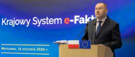 Zbigniew Stawicki, Podsekretarz Stanu w Ministerstwie Finansów, Zastępca Szefa Krajowej Administracji Skarbowej, przy mównicy, w tle ekran z prezentacją o KSeF 