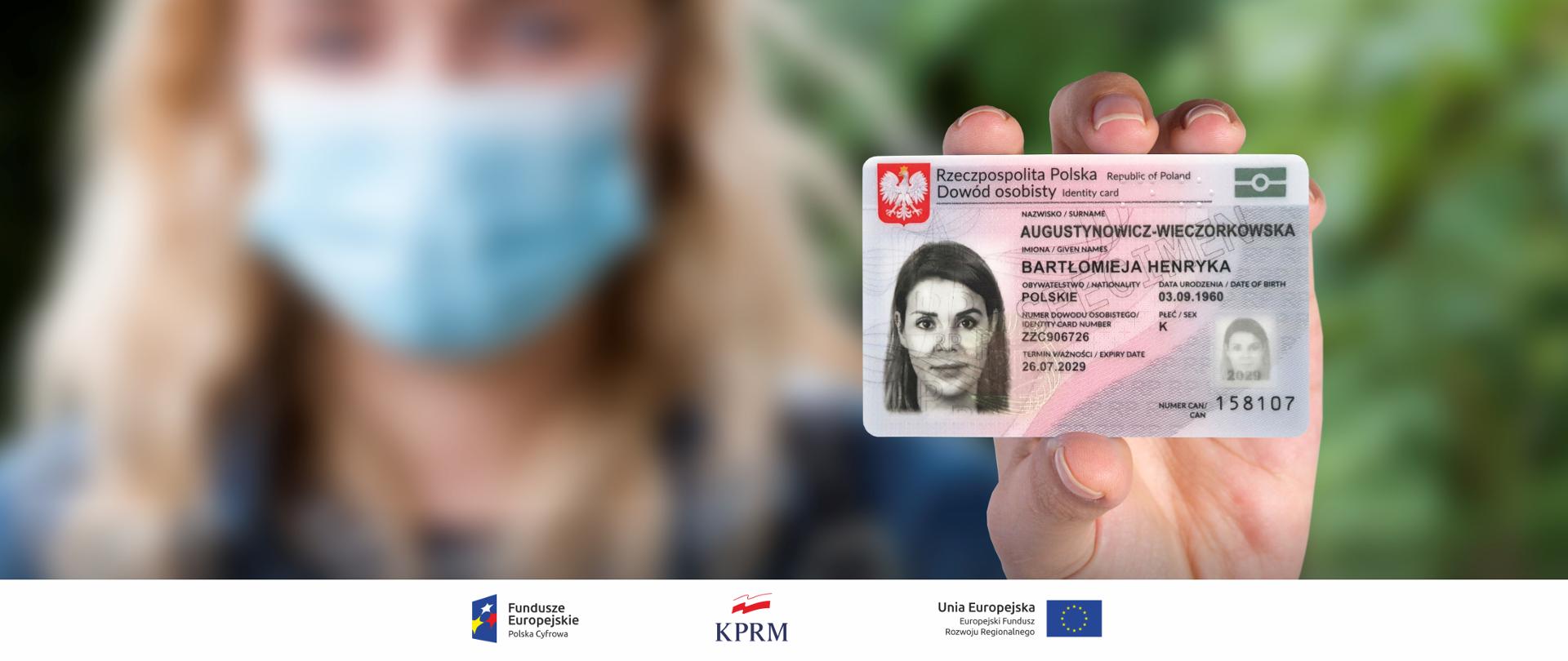 Kobieta w maseczce trzymająca w wyprostowanej ręce dowód osobisty - zbliżenie na dokument. Kobieta - na drugim planie, nieostra.