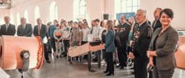 W jasnym korytarzu stoi duża grupa ludzi.