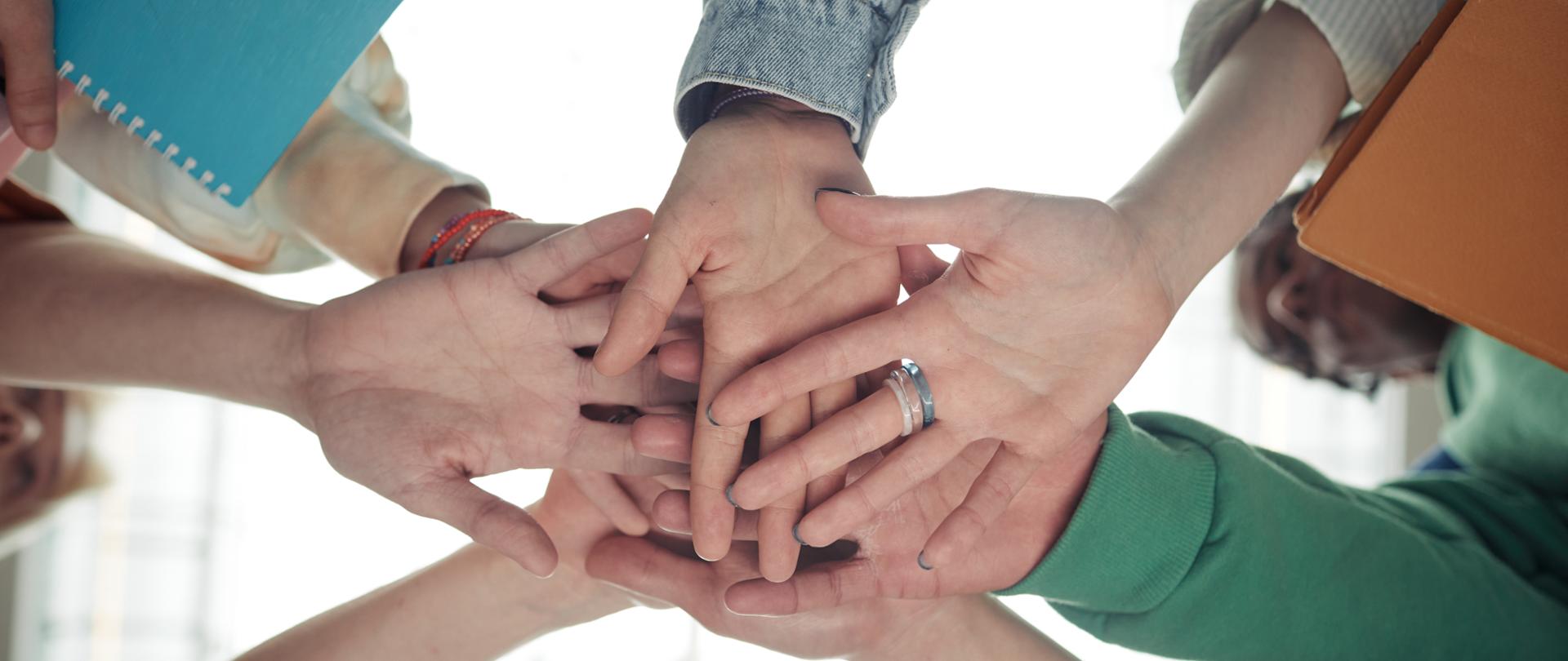Below angle of pile of hands of group of teenage students in casualwear as symbol of teamwork, support, friendship and unity