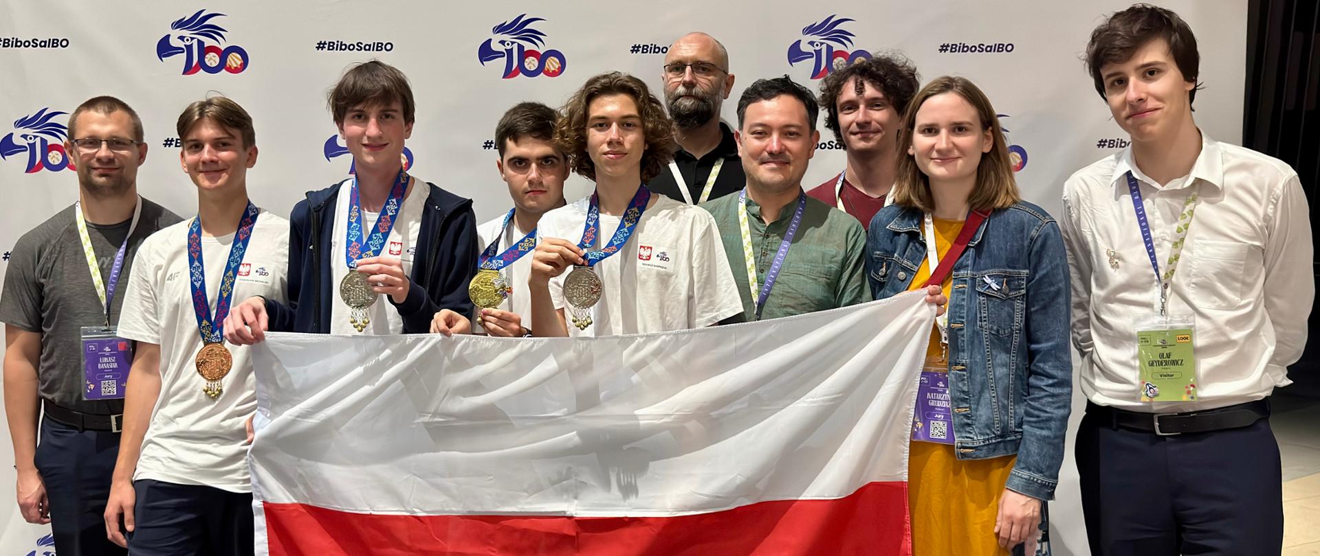 Na zdjęciu widać uczestników olimpiady z opiekunami, trzymają flagę Polski.