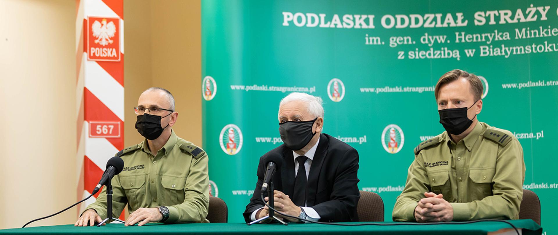 Na zdjęciu widać wicepremiera, przewodniczącego Komitetu ds. Bezpieczeństwa Narodowego i Spraw Obronnych Jarosława Kaczyńskiego, komendanta głównego gen. dyw. SG Tomasza Pragi i komendanta podlaskiego oddziału SG płk SG Andrzeja Jakubaszka siedzących za stołem w trakcie konferencji prasowej.