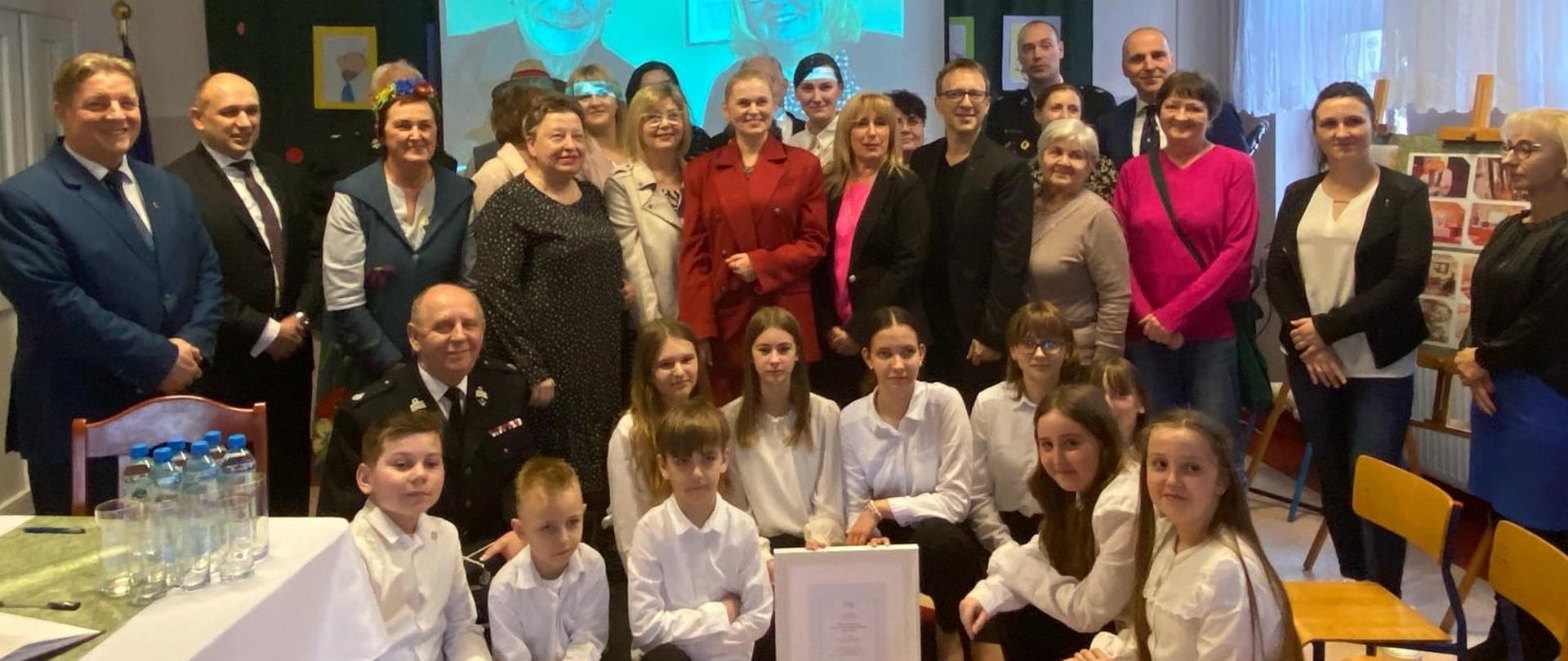 Zdjęcie zbiorowe, na sali stoi duża grupa ludzi i pozuje do zdjęcia, wśród nich minister Barbara Nowacka