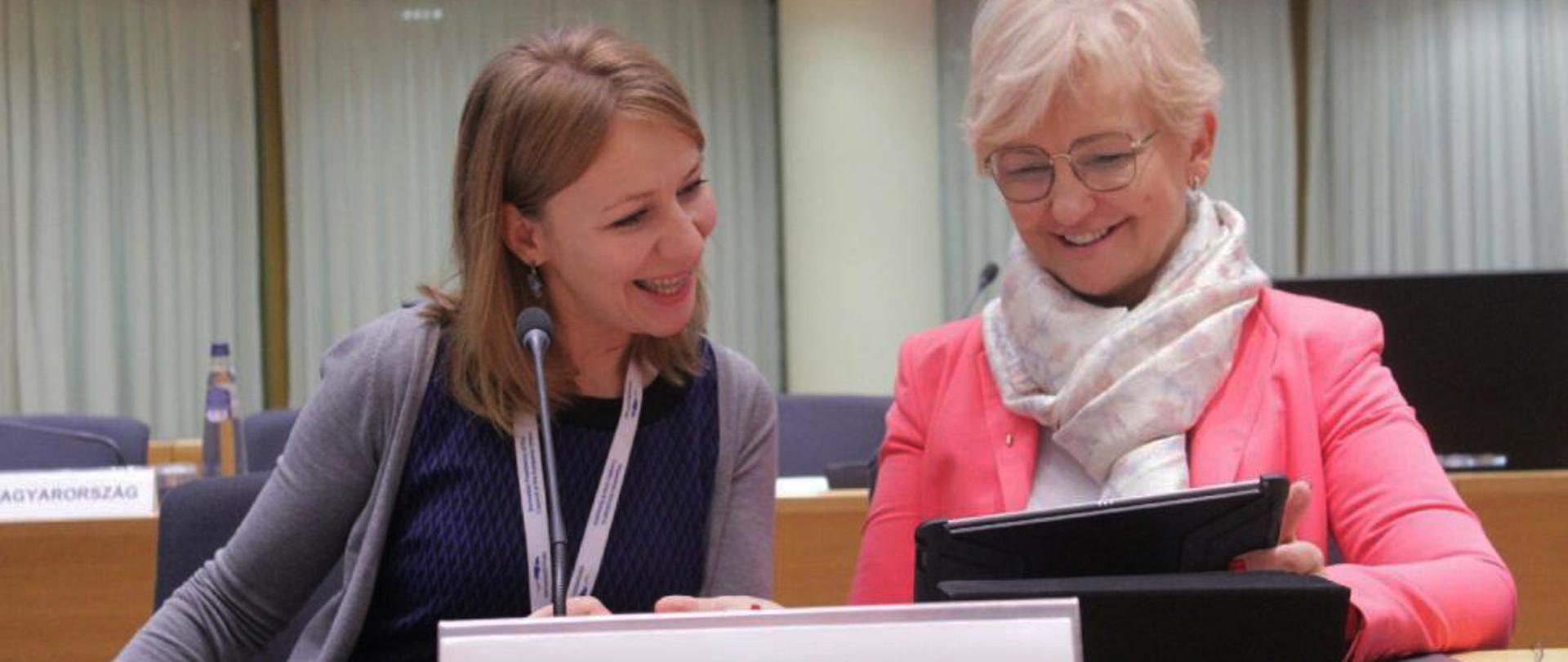 Minister Iwona Machałek siedzi przy stole na sali obrad. Na pierwszym planie tabliczka z napisem Polska. 